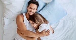 Happy couple in Sugar Land, TX, hugging in bed after BioTE Hormone Replacement Therapy